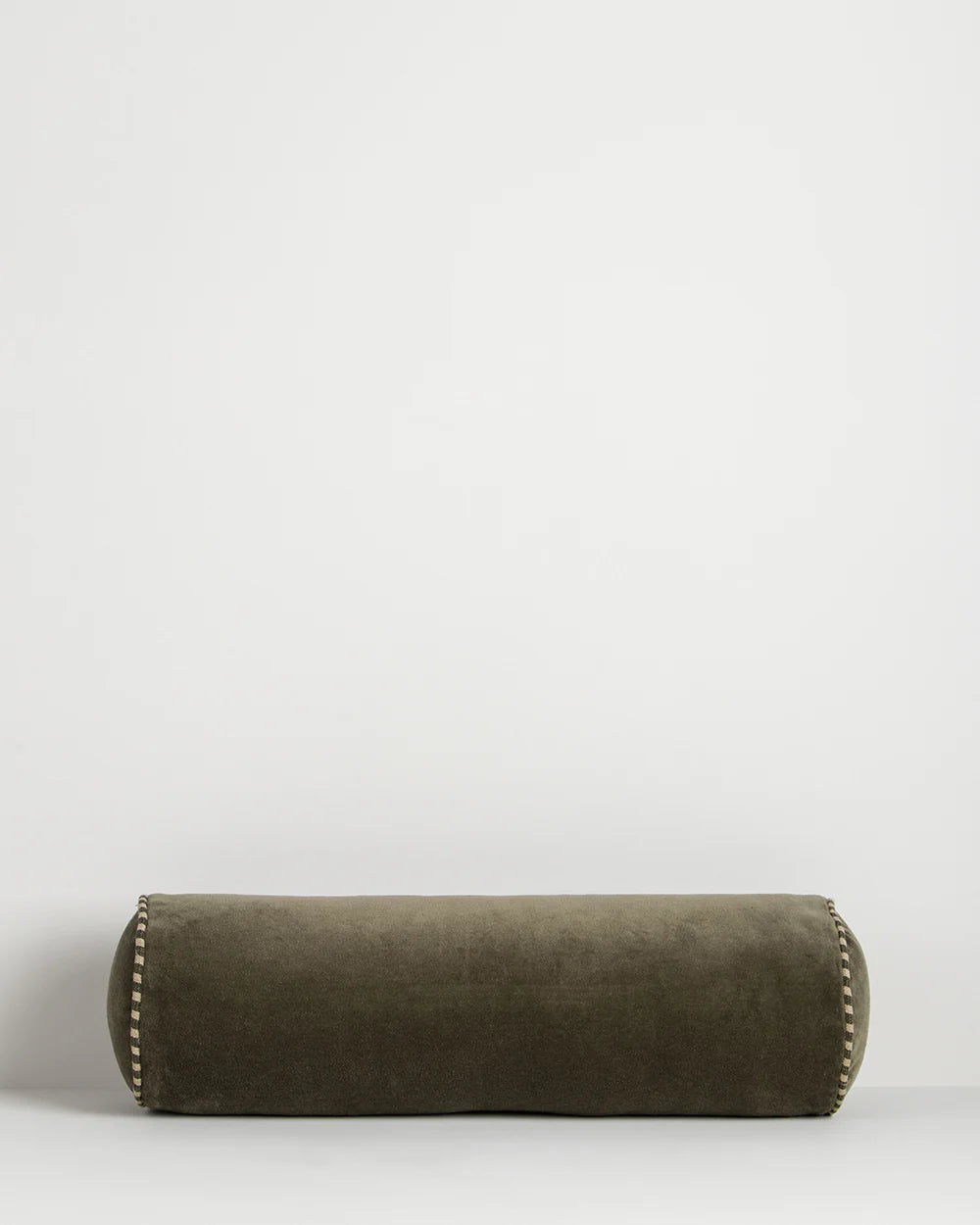 Green cylindrical pillow with decorative stitching on a white background